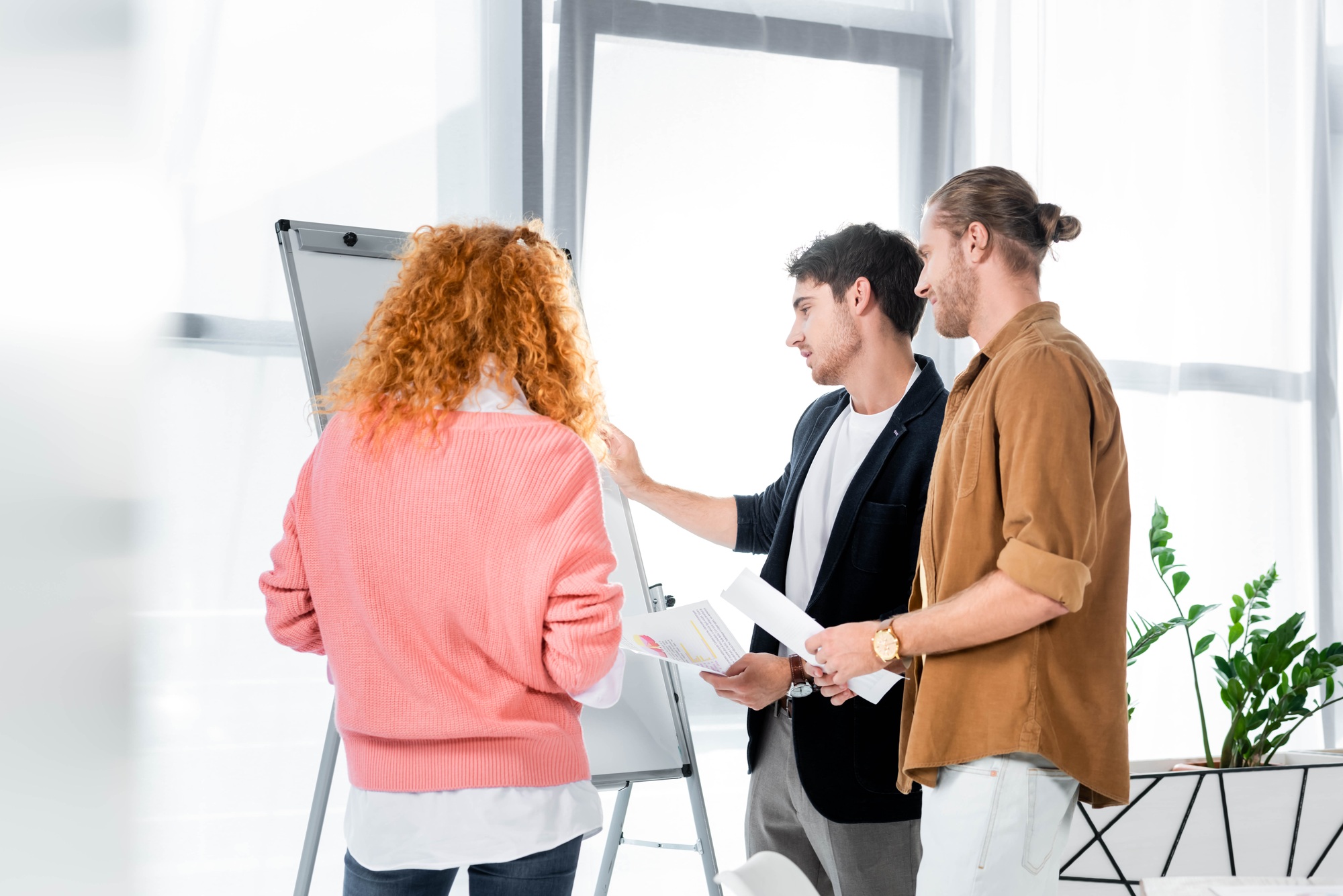 three friends doing paperwork and looking at flipchart in office